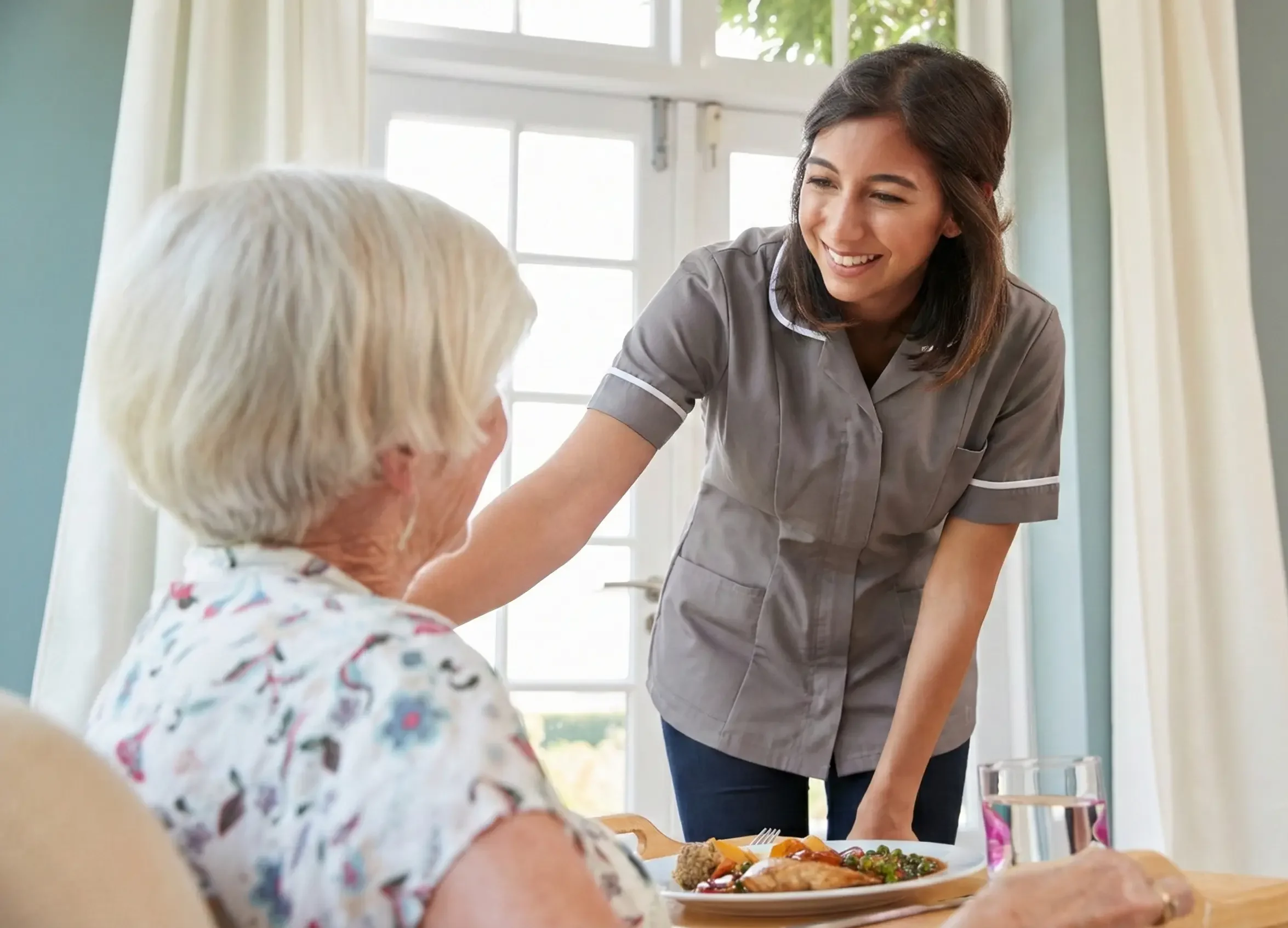 Professional home care smiling with elderly client indoors. SD Care